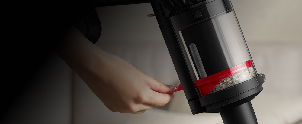 A person compressing dirt inside the bin of the Dyson Piston Animal vacuum.