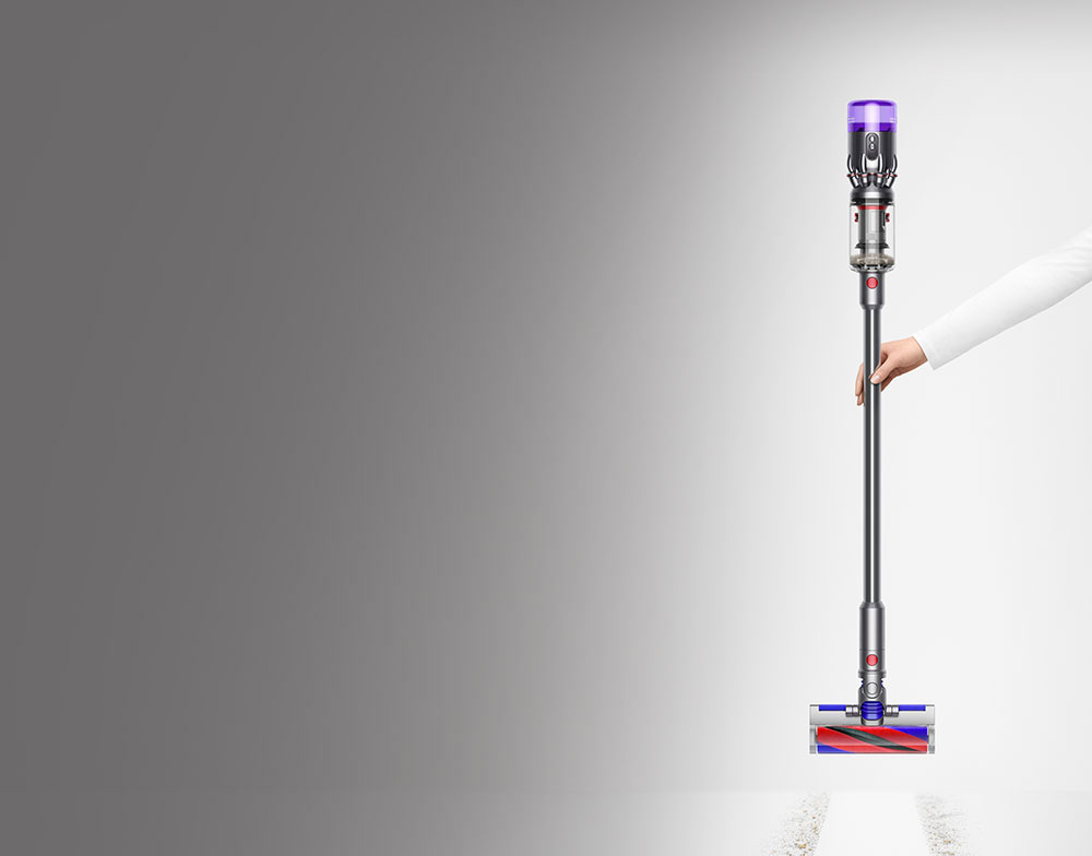 Woman vacuuming hard floor around sofa with the Dyson Omni-glide™ vacuum.