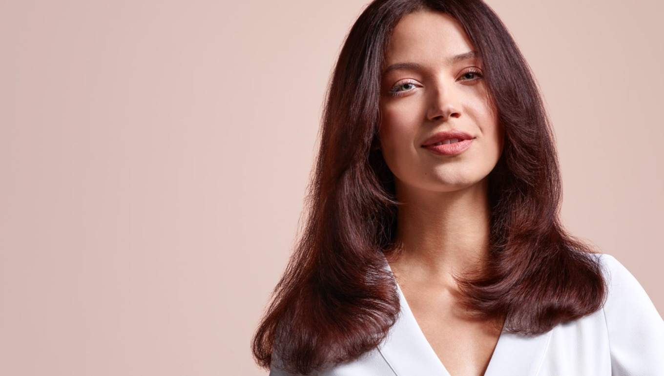 A model with mid-length brunette hair, wearing a volumised straight style.