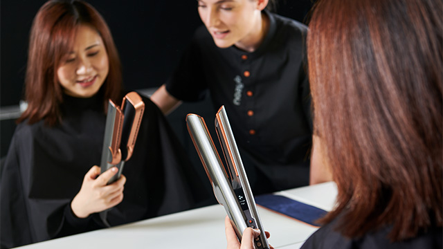 A customer in the Dyson Demo Store tries out the Dyson Airstrait straightener, helped by a Dyson Expert.