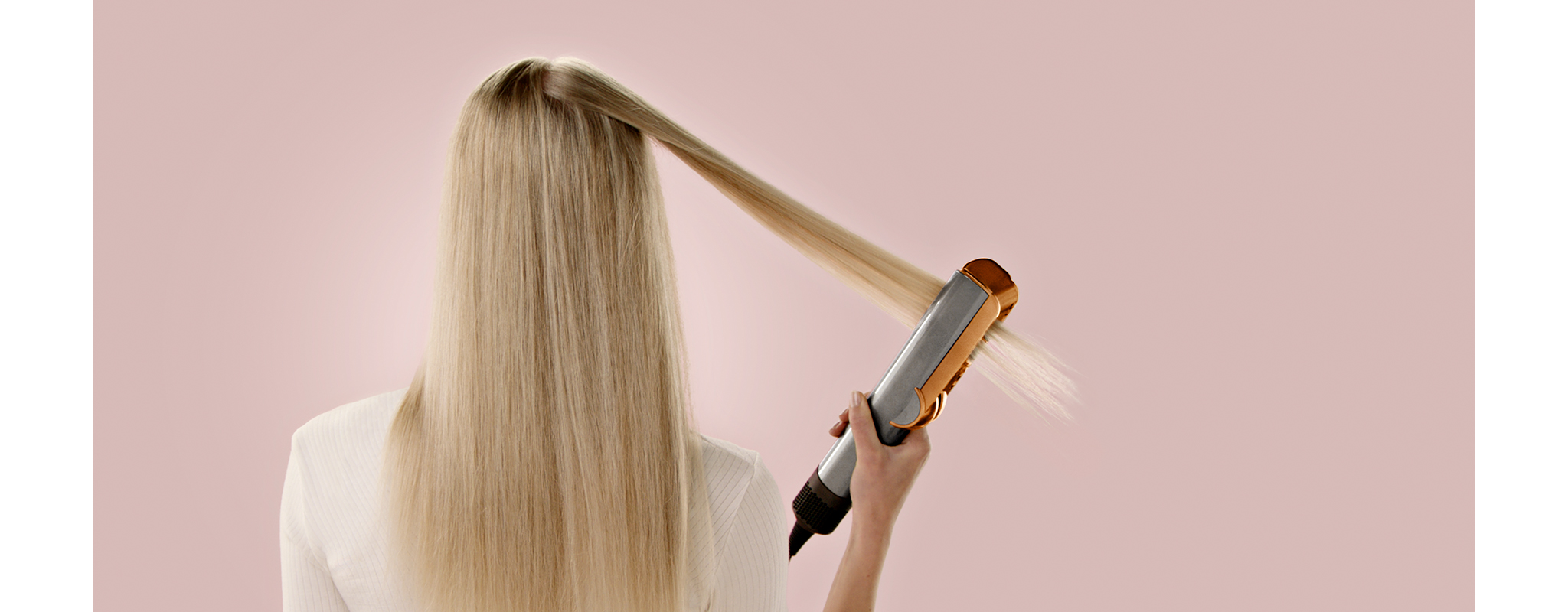 A model uses a Dyson Airstrait on a tress of hair.