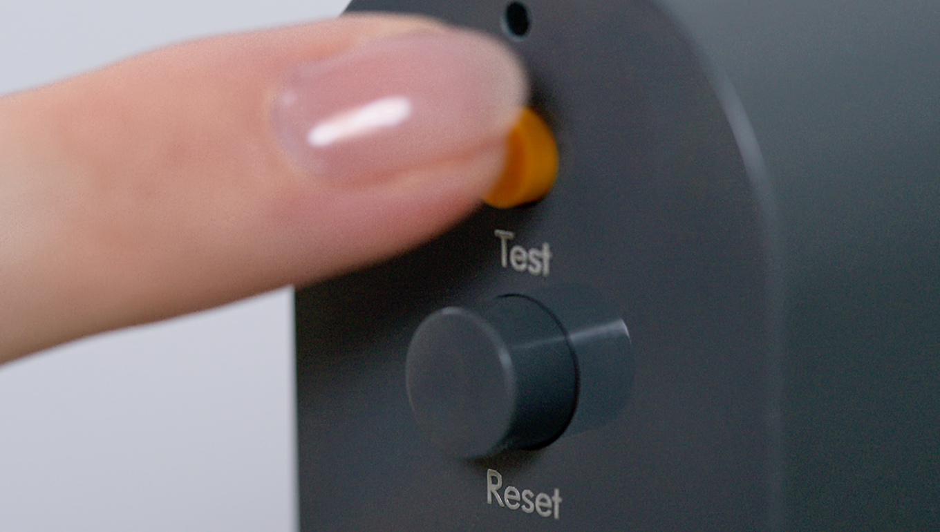 A finger pressing the test button on the PRCD plug